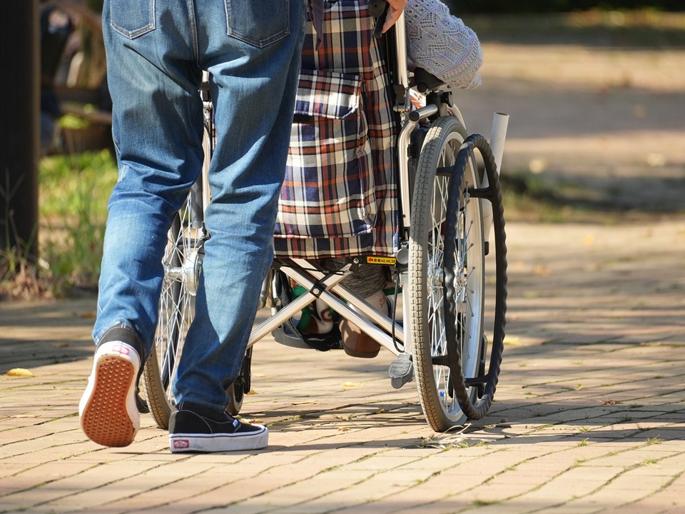 車いすで移動している高齢者と介護士