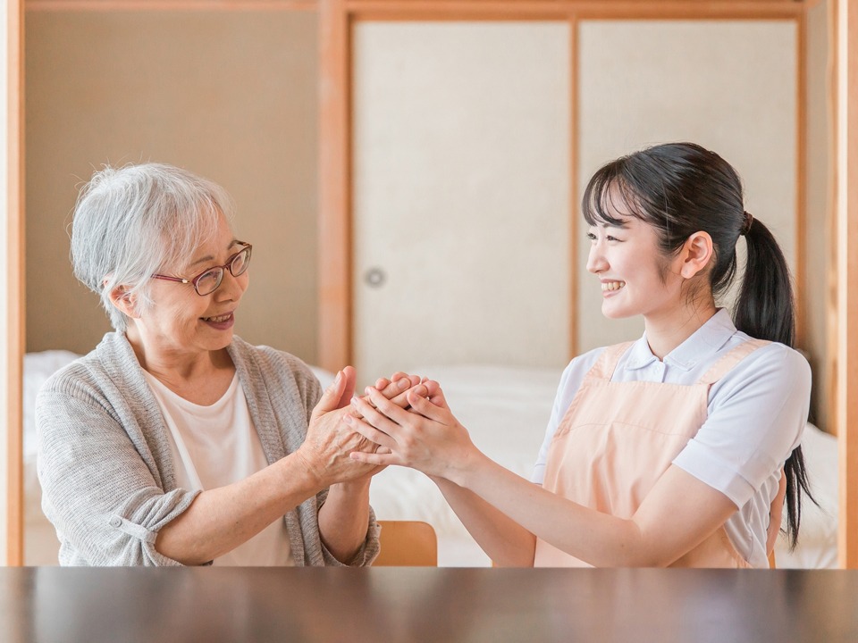 椅子に座り、にこやかに談笑している高齢者と介護士