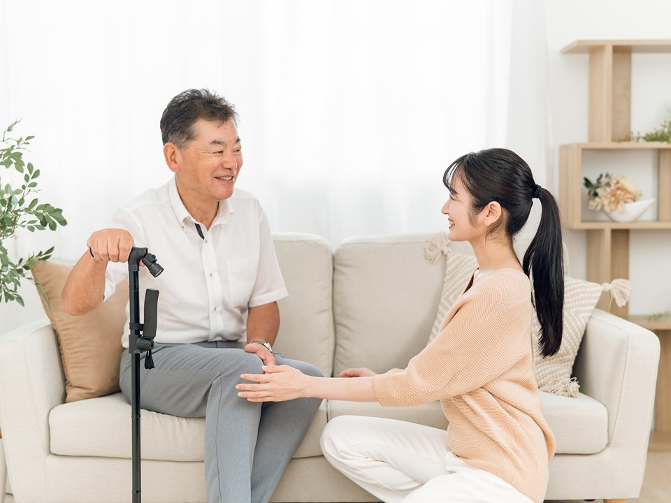 足に不自由のある高齢者ににやさしく話しかけている介護士